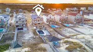 Zona residencial frente a la playa con varias casas, algunas con balcones y un área de piscina.