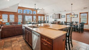 Una cocina amplia con una isla grande, muebles de madera y un comedor con múltiples sillas.
