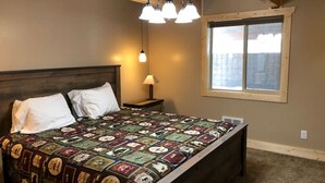 Un dormitorio con una cama grande, una mesita de noche, una lámpara y una ventana.