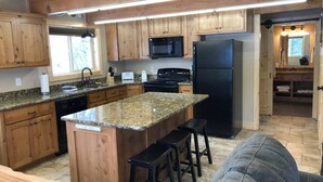 Una cocina compacta con armarios de madera, encimeras de granito y una isla central con taburetes de bar.
