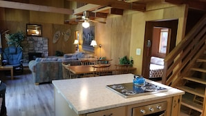 A cozy living area with a sofa, dining table, and kitchen island with a stove. - PinecrestAreaRentals #17  Fun cabin Summer 3rd night free. Just Book 2nights. (Cold Springs)