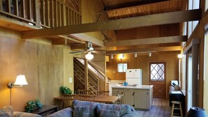 A cozy cabin interior with a wooden dining area, a sofa, a kitchen with a refrigerator, and a staircase. - PinecrestAreaRentals #17  Fun cabin Summer 3rd night free. Just Book 2nights. (Cold Springs)