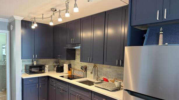 A modern kitchen with dark cabinets, a stainless steel refrigerator, a microwave, and a sink. - Your Summer Escape Awaits!!!  Walking distance to the pristine WWC beaches!!! (Wildwood Crest)