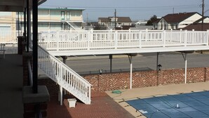 A covered outdoor area with a white railing, a brick wall, and a blue mat on the ground. - Your Summer Escape Awaits!!!  Walking distance to the pristine WWC beaches!!! (Wildwood Crest)