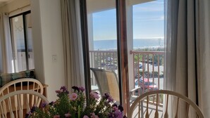 En balkon med udsigt til havet og parkerede biler.