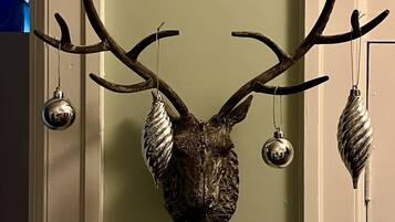 A deer head mounted on a door with antlers and two hanging ornaments.