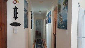 Käytävä, jossa on sininen matto, valkoiset seinät ja erilaisia kehystettyjä tauluja.