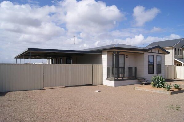 A single-story house with a covered patio, a fenced yard, and a small garden area.
