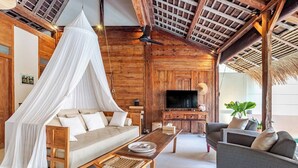 A cozy room with a canopy bed, a sofa, a dining table, and a TV.