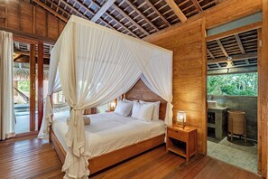 Un letto a baldacchino in legno con biancheria bianca, due comodini con lampade e vista su un paesaggio naturale attraverso una finestra.
