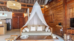 A cozy room with a wooden ceiling, a canopy bed, a wooden table, and a television.