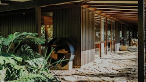 A covered outdoor area with a stone floor, wooden beams, and a large cylindrical planter. - Blue Gum Retreat- Stunning View and Cosy (Bellingen)