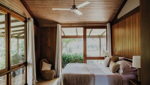 A bedroom with a large bed, wooden ceiling, and a view of greenery outside. - Blue Gum Retreat- Stunning View and Cosy (Bellingen)