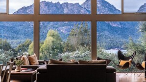 A room with large windows offering a mountain view, a sofa, a chair, and a small table with a plant. - The Loft - Freycinet Holiday houses (Coles Bay)