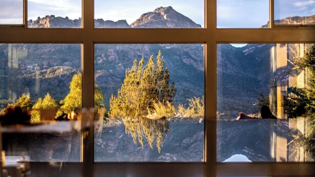 A view through a window with a reflection of a mountain and trees in a body of water. - The Loft - Freycinet Holiday houses (Coles Bay)