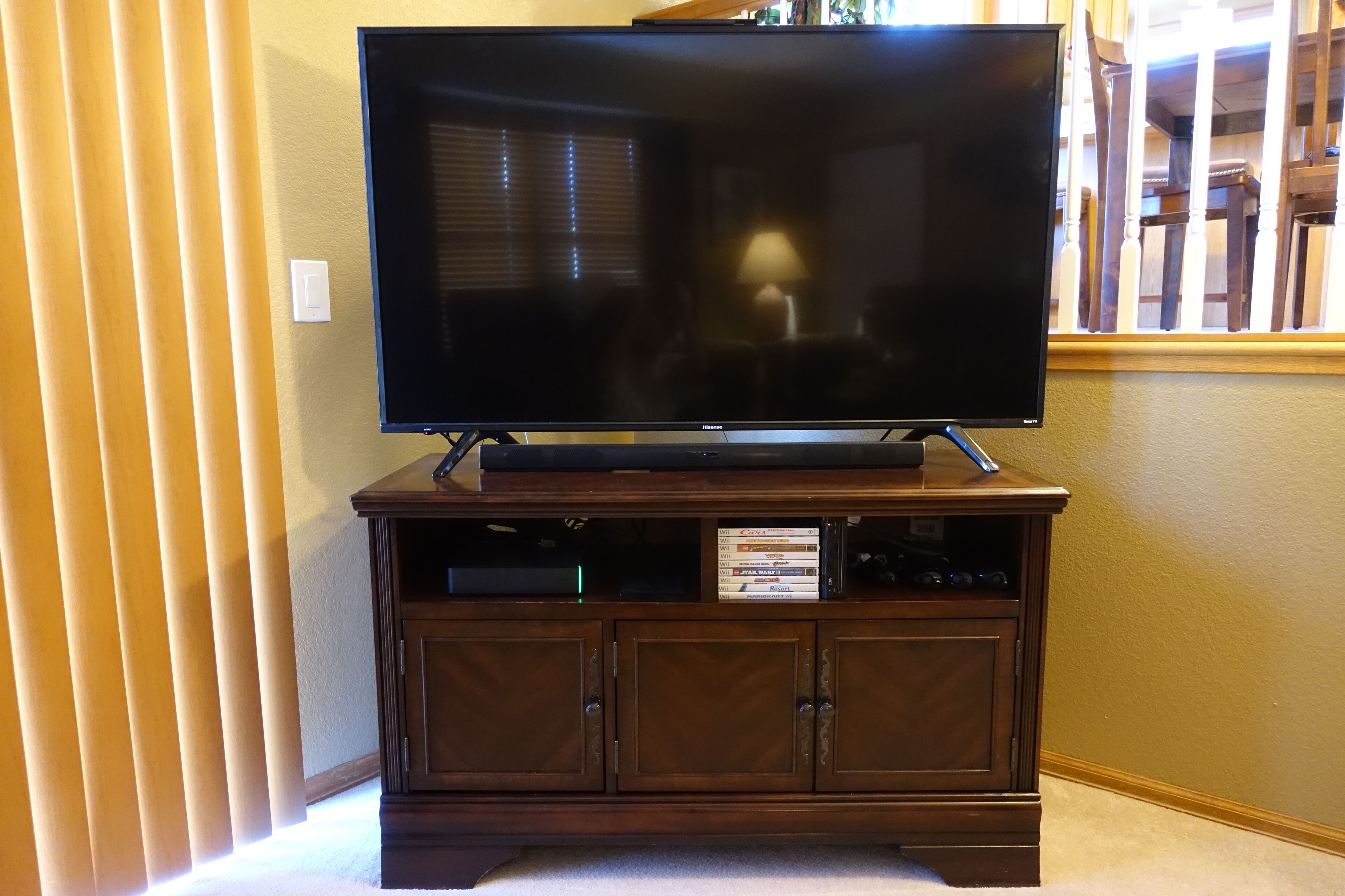 A flat-screen TV on a wooden stand with a cabinet below.