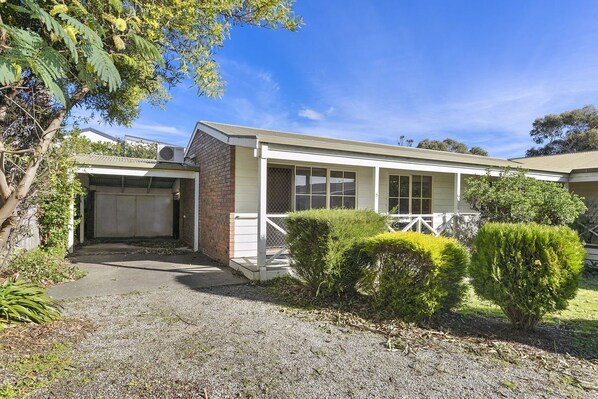A single-story house with a garage, a covered porch, and a well-maintained front yard with shrubs.