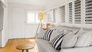 En stue med sofa, rundt træbord og gulvlampe.