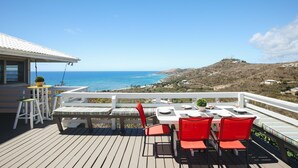 A deck with a table set for dining, overlooking a coastal landscape. - Paradise Awaits (Christiansted)