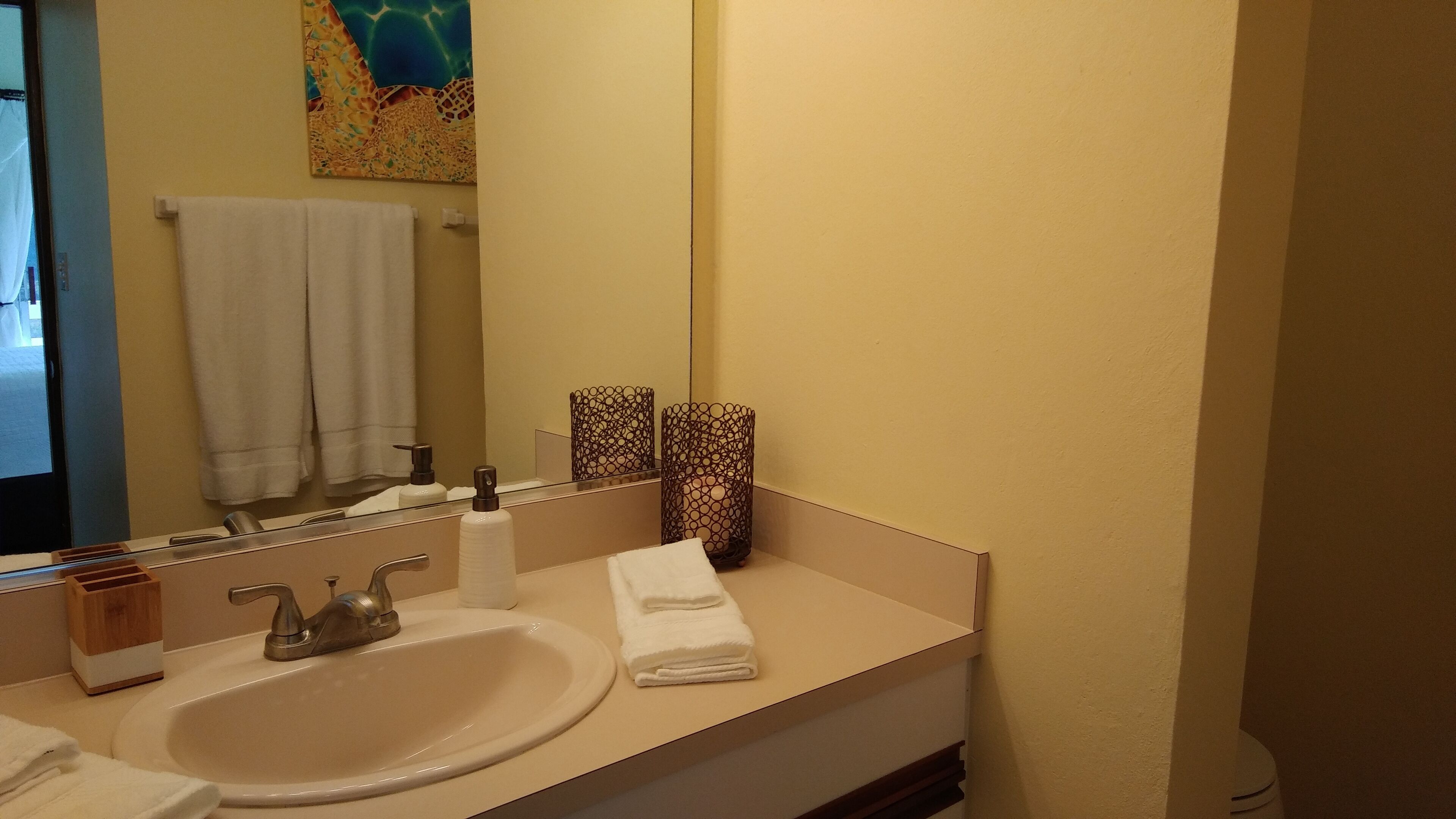 A bathroom with a sink, mirror, towel rack, and decorative items.