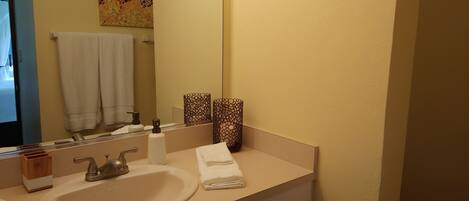 A bathroom with a sink, mirror, towel rack, and decorative items.