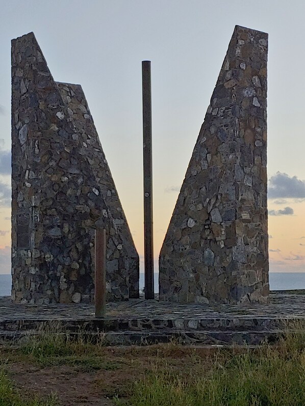 A stone structure with two large triangular walls and a central vertical pole.