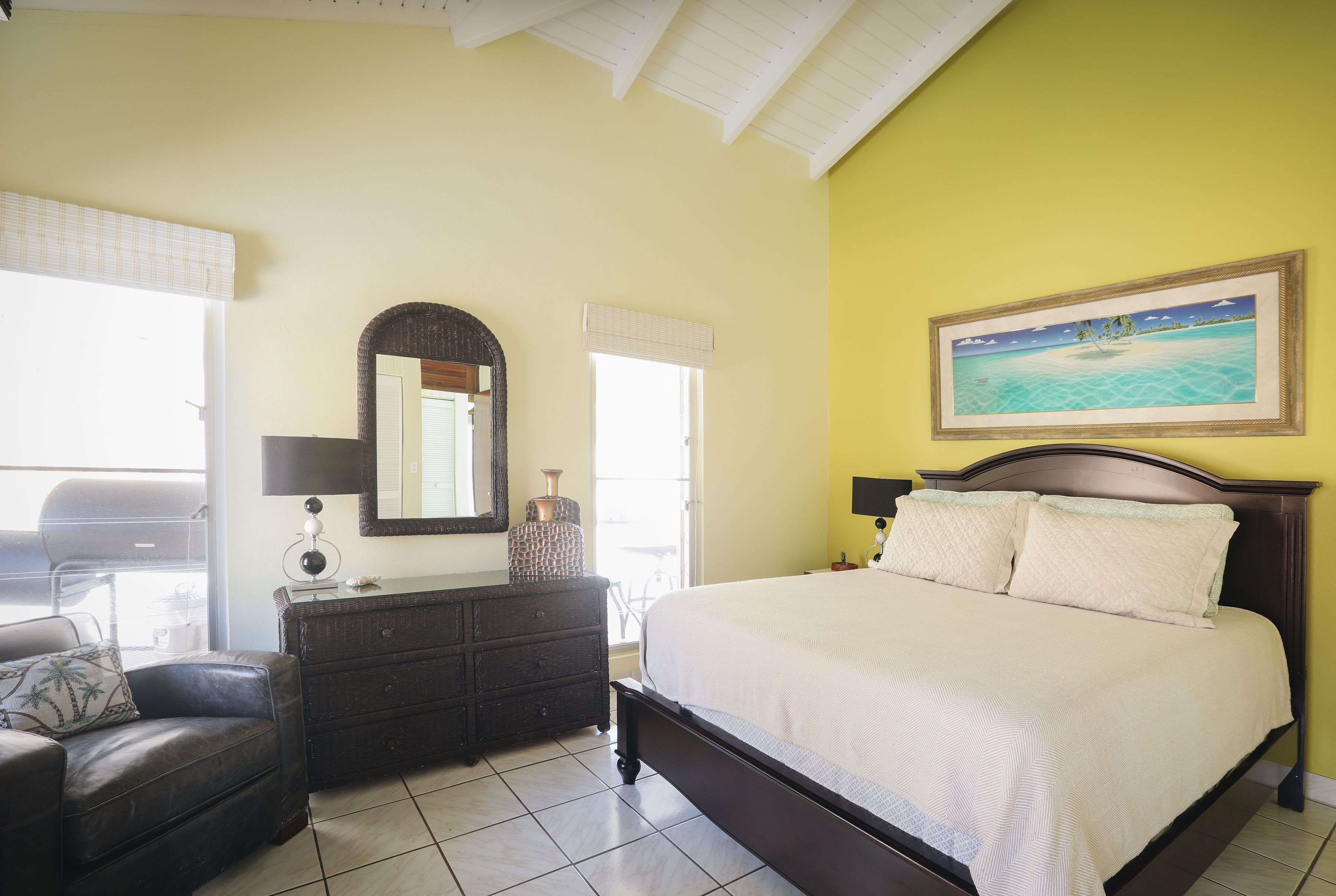 A bedroom with a bed, dresser, and a large mirror.