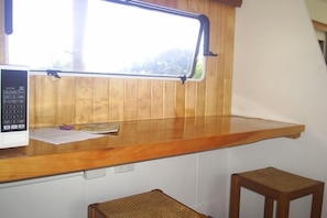 A kitchen with a wooden countertop, a microwave, and a window with a view of greenery.