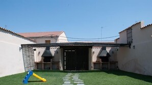 A courtyard with a paved path leading to a black gate, surrounded by white walls and a covered patio area. - House Tradition Rural for 16-20 people (Nieva)