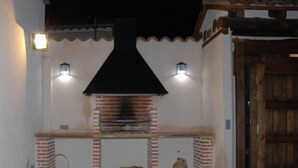 An outdoor brick oven with two wall-mounted lights, a rustic wooden door, and a small stone structure. - House Tradition Rural for 16-20 people (Nieva)