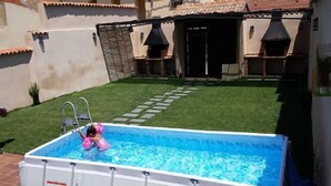 An outdoor swimming pool with a child playing in it, surrounded by a well-maintained lawn and a building with a tiled roof. - House Tradition Rural for 16-20 people (Nieva)