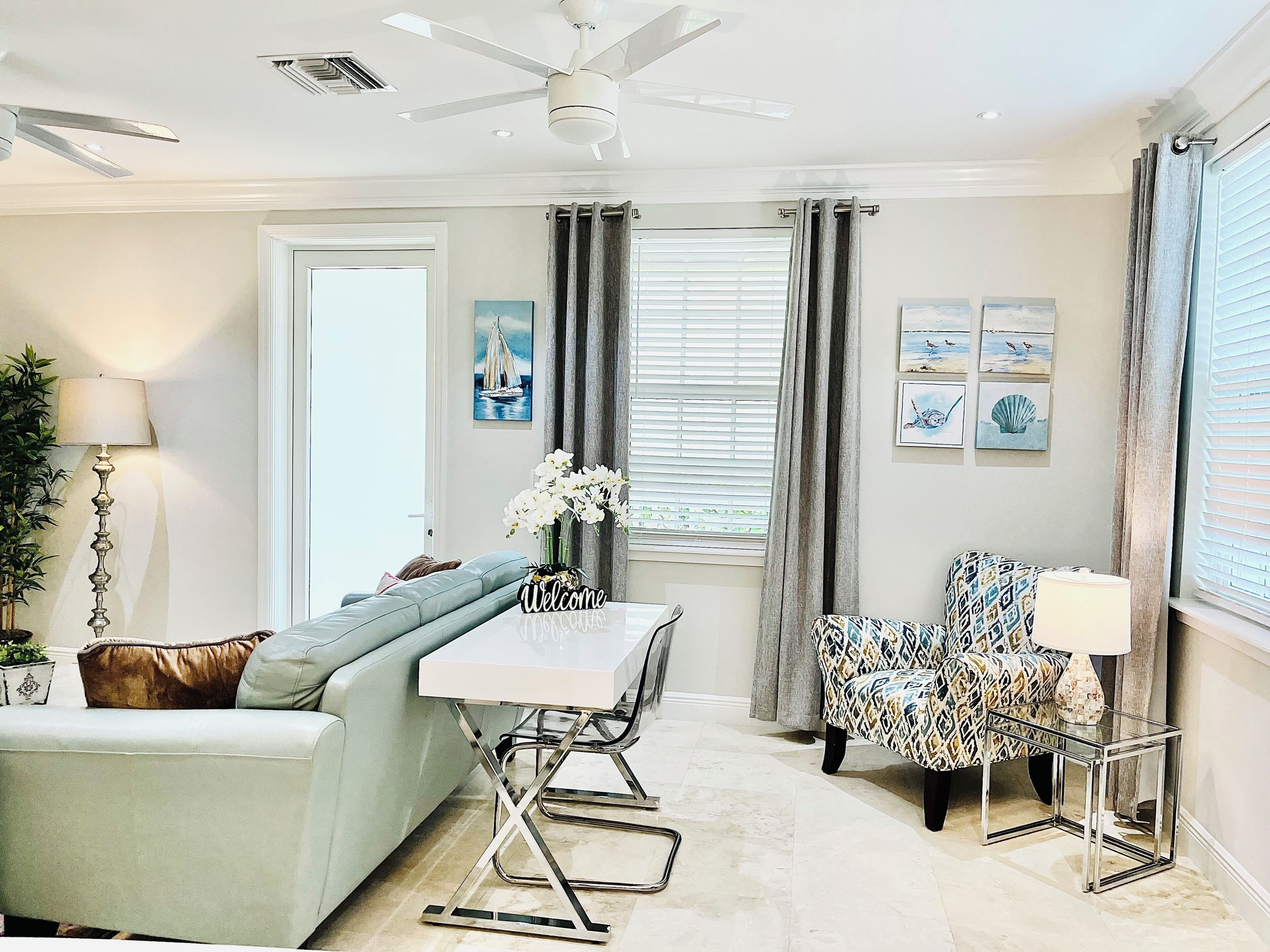 A modern living room with a sofa, a coffee table, a patterned armchair, and a ceiling fan.
