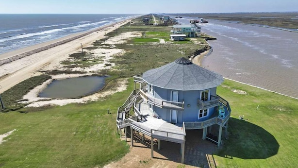 Una propiedad costera con un edificio circular grande, una playa y un estanque pequeño.