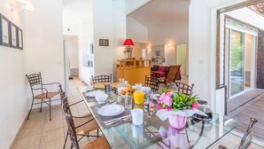 Un coin repas avec une table en verre, dressée pour quatre personnes, entourée de chaises en osier.