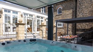 A hot tub area with a stone wall and a covered seating area. - Coedrath House - Luxury Manor, Swim Spa, Sea Views (Saundersfoot)