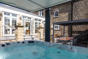 A hot tub area with a stone wall and a covered seating area. - Coedrath House - Luxury Manor, Swim Spa, Sea Views (Saundersfoot)