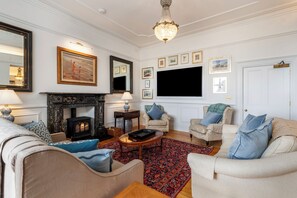 Una sala de estar con chimenea, sofás, una mesa de centro y una televisión.