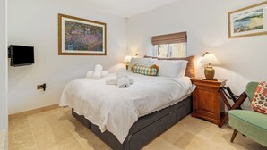 A hotel room with a bed, two bedside lamps, a television, and two framed artworks on the walls. - Coedrath House - Luxury Manor, Swim Spa, Sea Views (Saundersfoot)