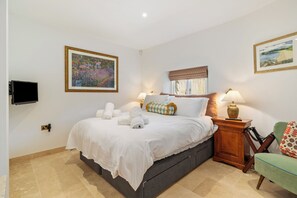 A hotel room with a bed, two bedside lamps, a television, and two framed artworks on the walls. - Coedrath House - Luxury Manor, Swim Spa, Sea Views (Saundersfoot)