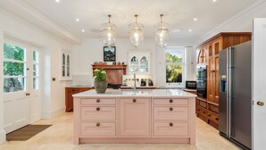 A spacious kitchen with a large island, modern appliances, and a view of the outdoors. - Coedrath House - Luxury Manor, Swim Spa, Sea Views (Saundersfoot)