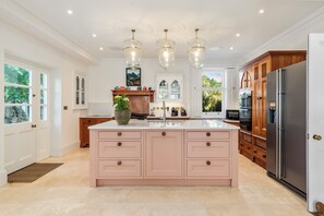 A spacious kitchen with a large island, modern appliances, and a view of the outdoors. - Coedrath House - Luxury Manor, Swim Spa, Sea Views (Saundersfoot)