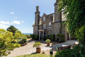 A stone building with a courtyard, potted plants, and a bench. - Coedrath House - Luxury Manor, Swim Spa, Sea Views (Saundersfoot)