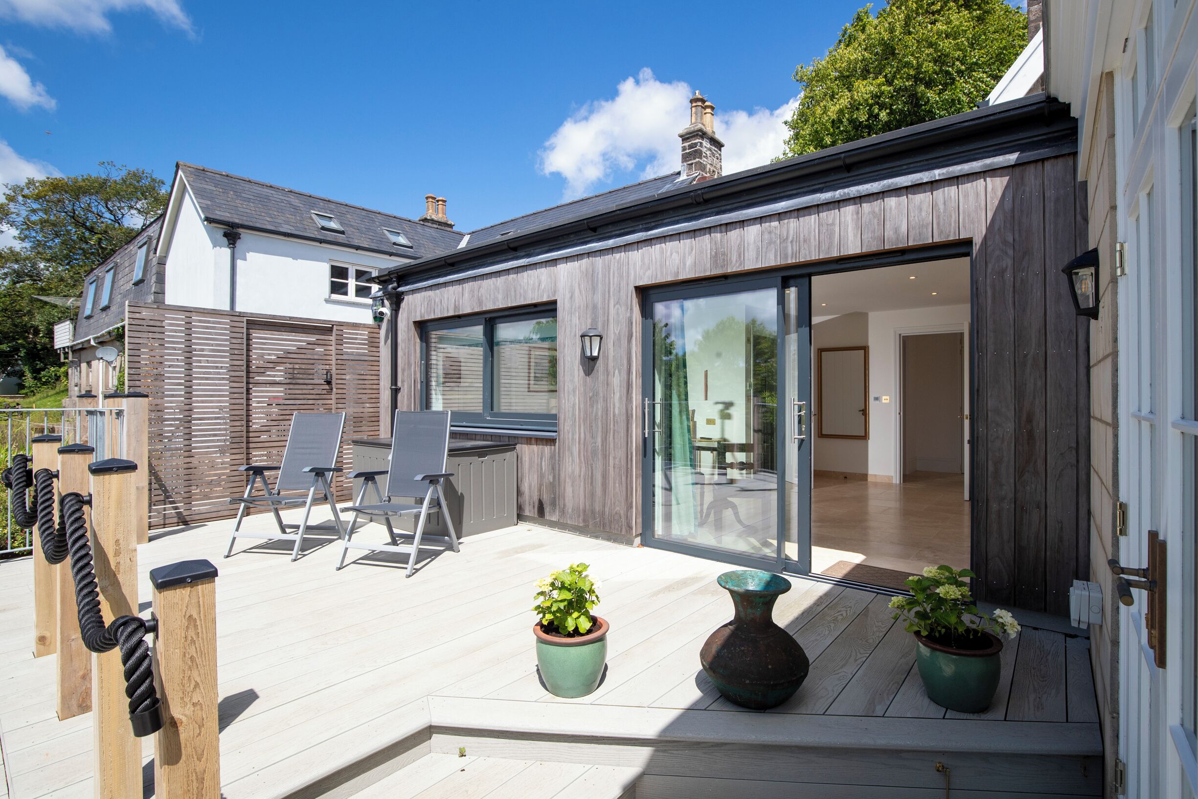 A modern house with a patio, outdoor seating, and potted plants.