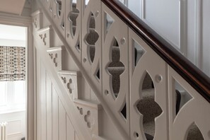 Una escalera con balaustres blancos y una barandilla de madera oscura.