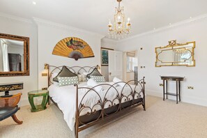 A bedroom with a four-poster bed, a chandelier, a large mirror, and a traditional fan. - Coedrath House - Luxury Manor, Swim Spa, Sea Views (Saundersfoot)
