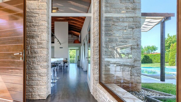 A modern interior with a stone wall, a wooden door, and a view of a swimming pool. - Beautiful private villa with hot tub, A/C, private pool, WIFI, TV, terrace and pets allowed (Pazin)