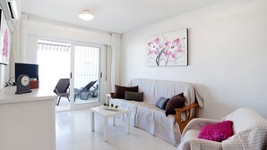 A modern living room with a sofa, a coffee table, and a painting on the wall. - Beautiful apartment for 4 people with A/C, pool, WIFI, TV and terrace (Calpe)