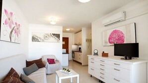 A modern living room with a sofa, a coffee table, and a TV on a white cabinet. - Beautiful apartment for 4 people with A/C, pool, WIFI, TV and terrace (Calpe)