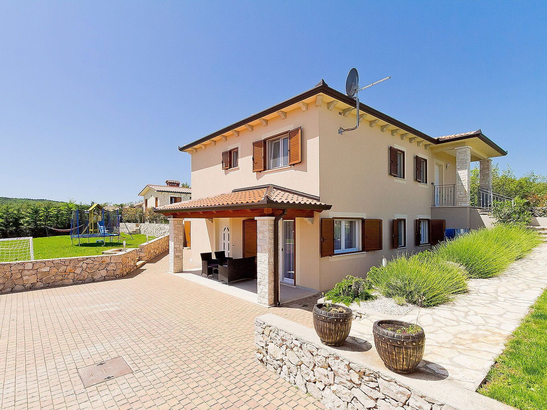 A two-story house with a patio, stone walls, and a satellite dish.