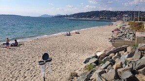 A beach with a rocky shoreline, people sunbathing, and a clear view of the sea. - Luxurious Beach Apartment, Juan Les Pins (Antibes)